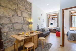 Ein gemütliches Wohnzimmer mit Steinwand, einer Essecke mit Tisch und Stühlen, einer Couch und einem Fernseher.