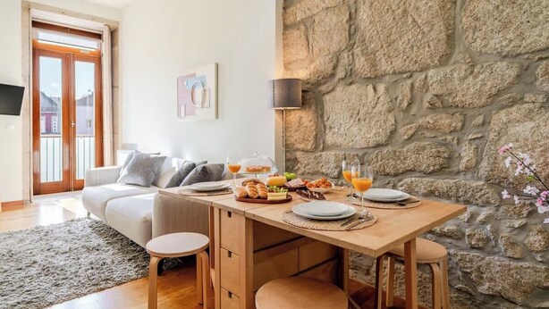 Ein Essbereich mit Steinwand, Holztisch und Stühlen.