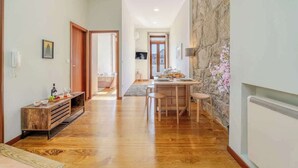 Ein geräumiger Flur mit Holzboden, ein Essbereich mit Tisch und Stühlen sowie eine Wand mit Steinverkleidung.
