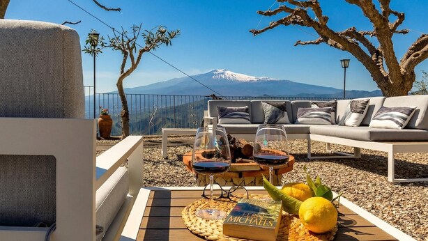 Eine Terrasse mit einer Couch, einem Tisch mit Buch und Gläsern sowie Blick auf die Berge.