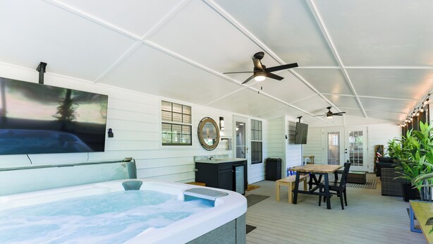 A spacious indoor area with a hot tub, ceiling fans, a dining table, and chairs. - Hot Tub, Pool Table, Ping-Pong, Private Playground, Fire Pit, Library, Play Room (Valdosta)