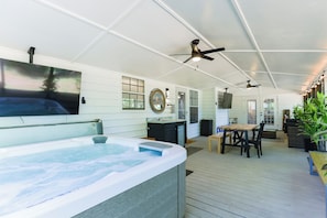 A spacious indoor area with a hot tub, ceiling fans, a dining table, and chairs.