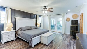 A bedroom with a bed, nightstands, a ceiling fan, and a view through a glass door. - Hot Tub, Pool Table, Ping-Pong, Private Playground, Fire Pit, Library, Play Room (Valdosta)