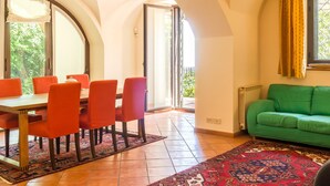 Un coin repas avec une table et des chaises, un canapé vert et un tapis à motifs.