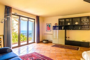 Ein Wohnzimmer mit Sofa, Couchtisch, Kamin und Blick ins Freie.