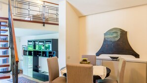 Un espace repas comprenant une table, des chaises, un élément décoratif mural et un escalier.