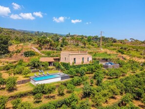 Ein Haus mit Swimmingpool, umgeben von Grünflächen und Hügeln.