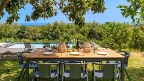 A wooden dining table with chairs, set for a meal with wine glasses, plates, and a vase of flowers. - Villa Tiaréa - Giarre (Giarre)
