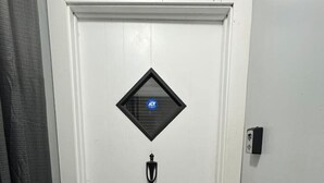 A white door with a security keypad, a peephole, and a small window with a sticker. - H1-Large 3 Bedroon 1.5 Bathroom apartment (Syracuse)
