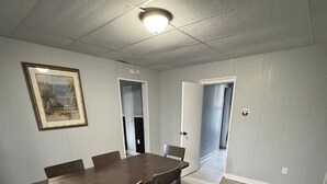 A room with a dining table, chairs, a framed picture on the wall, and a door leading to another room. - H1-Large 3 Bedroon 1.5 Bathroom apartment (Syracuse)