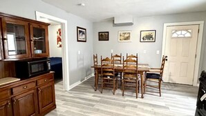 Ein Essbereich mit Holztisch und Stühlen, einer Mikrowelle und einem Schrank.