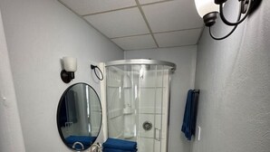 Une salle de bain comprenant des toilettes, un lavabo, un miroir, une cabine de douche et un porte-serviettes.