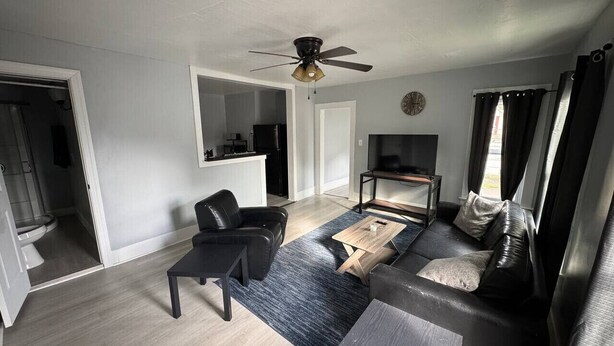Un salon moderne avec un canapé, une table basse, un téléviseur et un ventilateur de plafond.