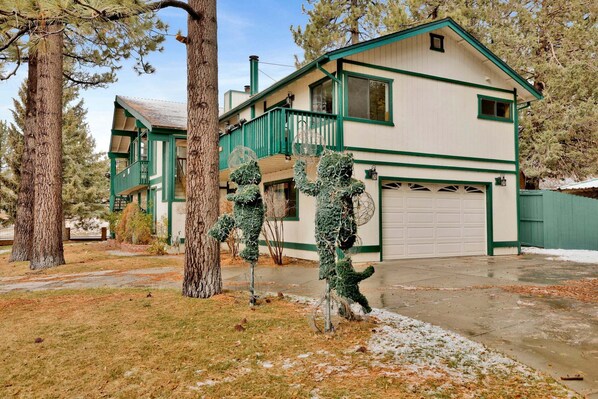 Une maison à deux étages avec un garage, entourée d’arbres et d’un paysage enneigé.