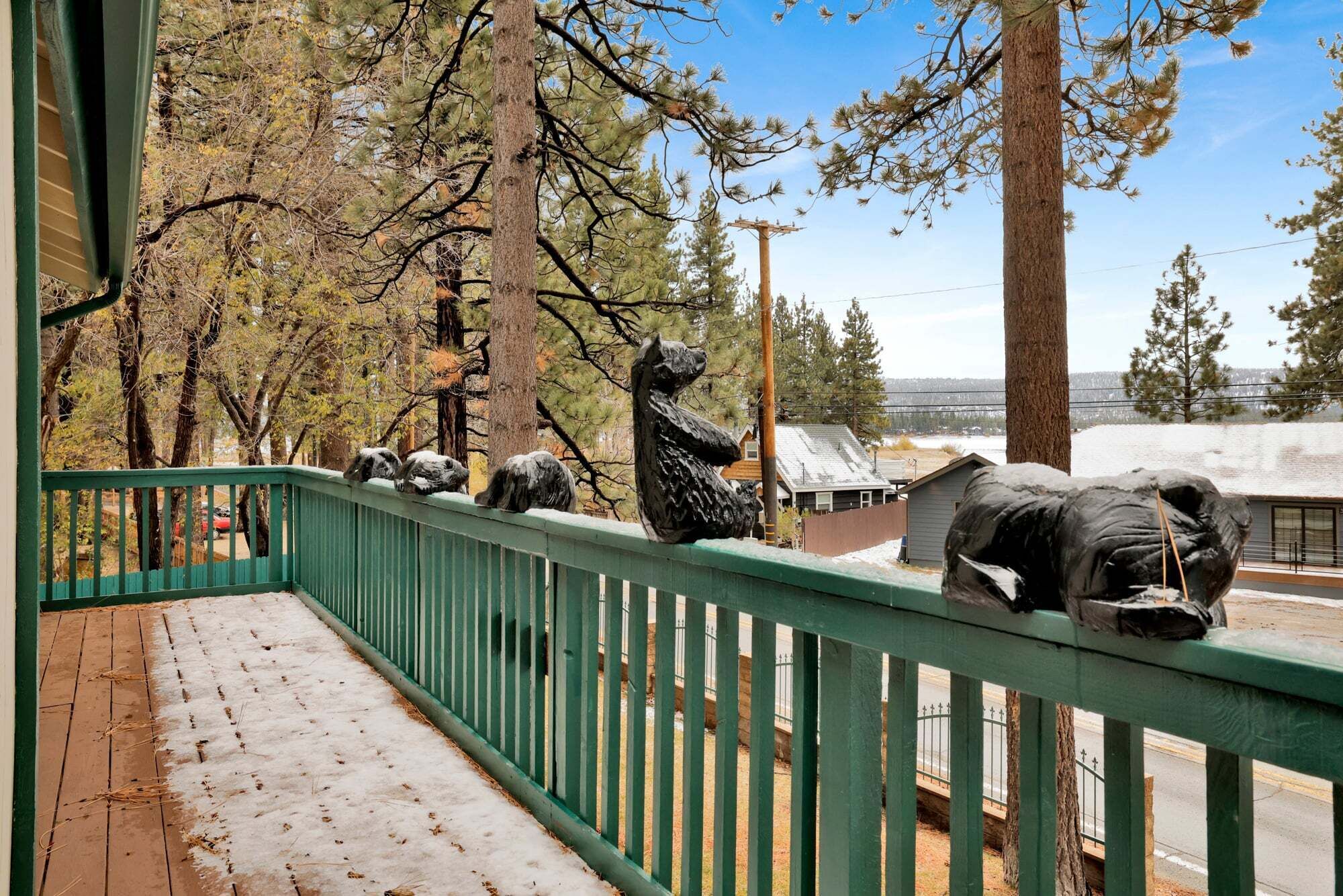Un pontile di legno con neve a terra, una ringhiera verde e una statua di un orso.