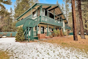A two-story lodge with a balcony, a covered porch, and a staircase leading to the upper level. - Vivienda de Osos #2549 (Fawnskin)