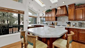 Una cocina con armarios de madera, una isla grande y una zona de comedor con sillas.
