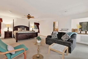 Une chambre à coucher avec un lit à baldaquin, un canapé, un fauteuil, une petite table et un ventilateur de plafond.