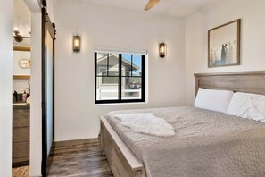 Ein Schlafzimmer mit Bett, Fenster und einem Gemälde an der Wand.