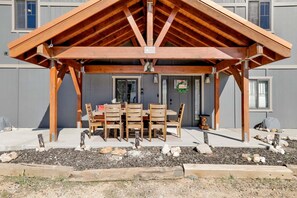 Ein überdachter Außenbereich mit Tisch und Stühlen, eine Tür mit der Beschriftung 'CABIN' und ein Gebäude mit Fenstern und einer grauen Fassade.