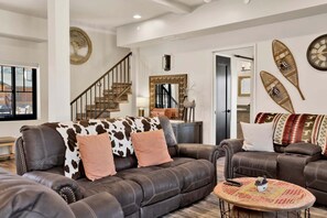 Ein Wohnzimmer mit einem braunen Ledersofa, einem runden Couchtisch und einer Treppe.