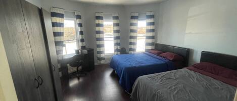 Ein Schlafzimmer mit zwei Betten, einem Schreibtisch und einem Stuhl.