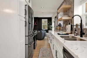 Eine moderne Küche mit großem Kühlschrank, Marmorarbeitsplatte und eingebautem Backofen.