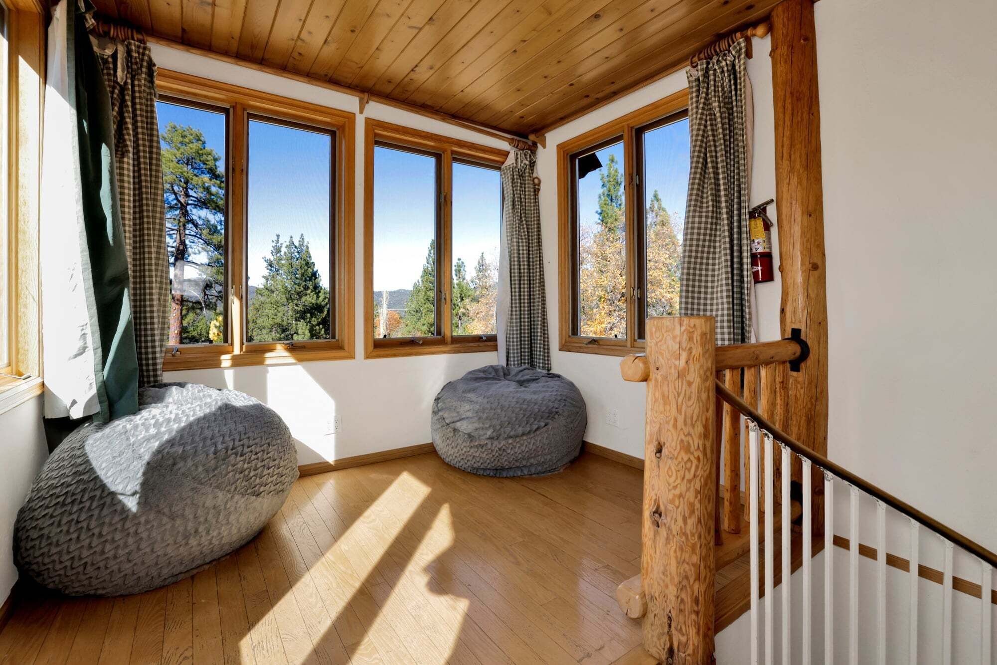 A room with wooden floors, large windows, and two bean bags. - 2597-the Village Timber Lodge (Big Bear Lake)