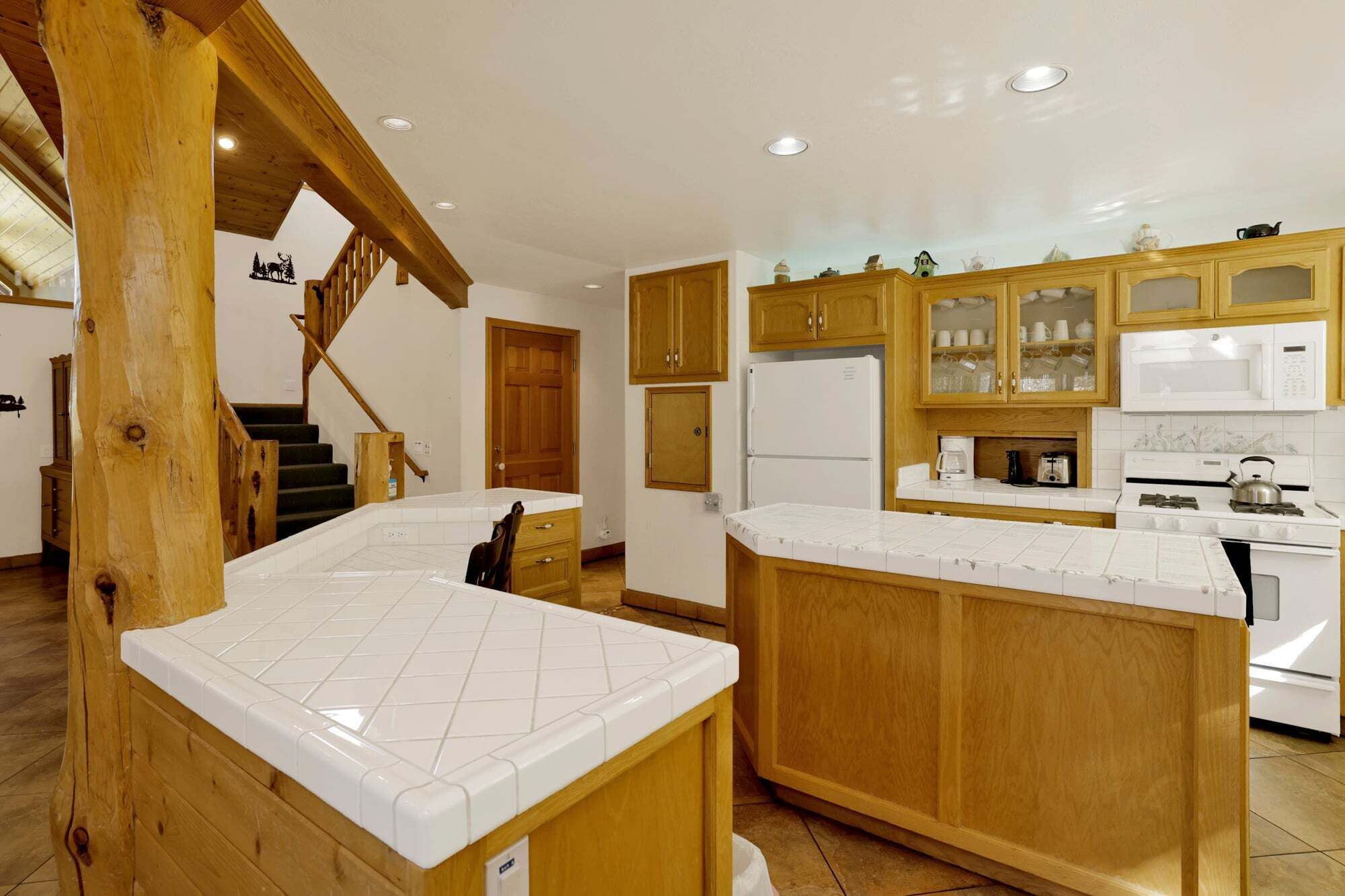 Una cocina con armarios de madera, encimera blanca y estufa empotrada.