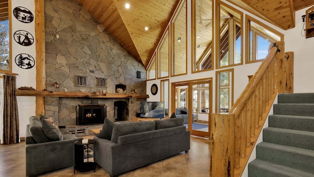 A spacious living area with a stone fireplace, a large sofa, and a wooden staircase. - 2597-the Village Timber Lodge (Big Bear Lake)