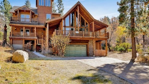 A large log cabin with multiple levels, a garage, and a prominent chimney. - 2597-the Village Timber Lodge (Big Bear Lake)