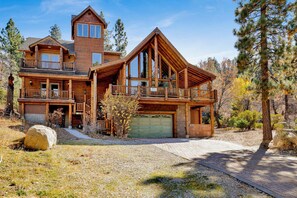 Eine große Blockhütte mit mehreren Ebenen, einer Garage und einem markanten Schornstein.