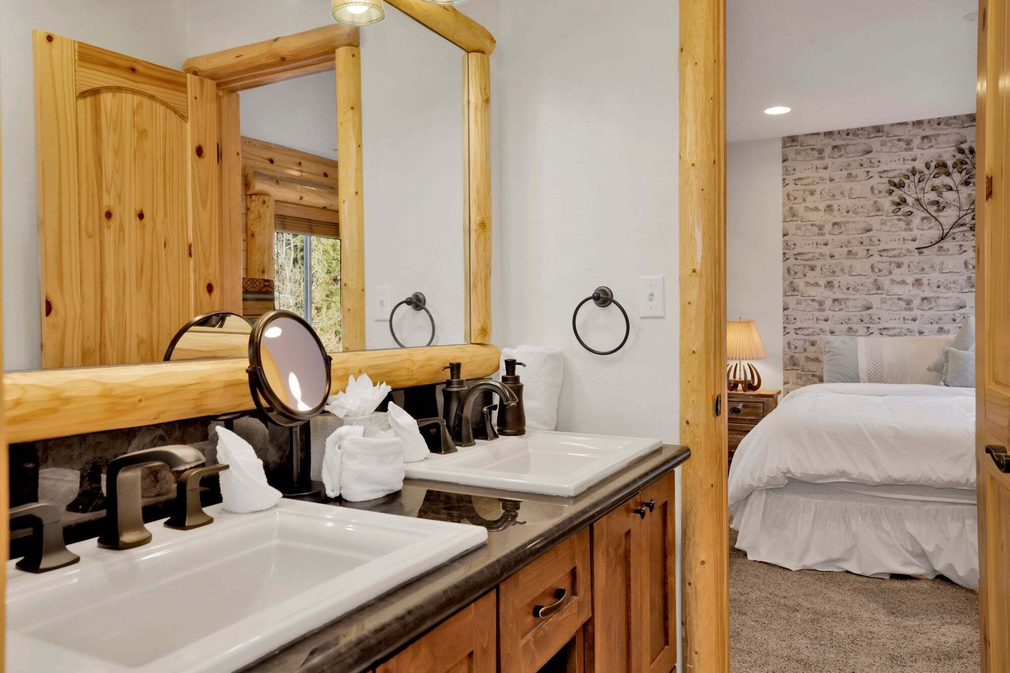 Une salle de bain avec deux lavabos, un miroir et un meuble-lavabo en bois.