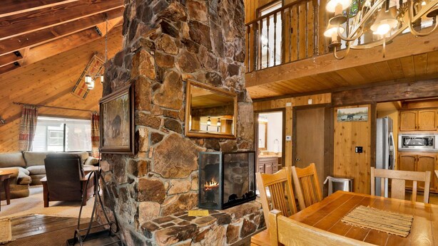 A rustic interior with a stone fireplace, wooden furniture, and a high ceiling. - 2605-crystal Pines (Big Bear Lake)