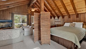 A log cabin bedroom with a bed, a television, a desk, and a large window. - 2605-crystal Pines (Big Bear Lake)