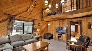A cozy cabin interior with a loft bedroom, a living area with a sofa, a coffee table, and a leather armchair. - 2605-crystal Pines (Big Bear Lake)