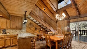 A wooden cabin interior with a kitchen, dining area, and a staircase. - 2605-crystal Pines (Big Bear Lake)
