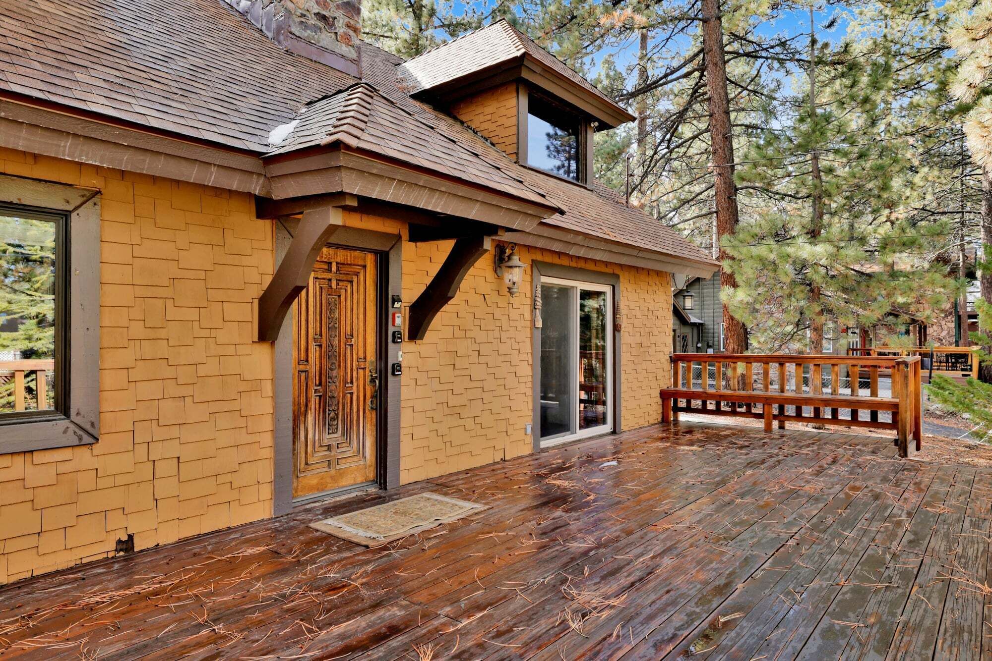 A wooden cabin with a brick exterior, a wooden deck, and a large window.
