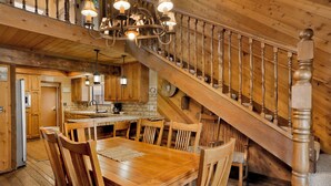 A wooden interior with a dining area, kitchen, and staircase. - 2605-crystal Pines (Big Bear Lake)