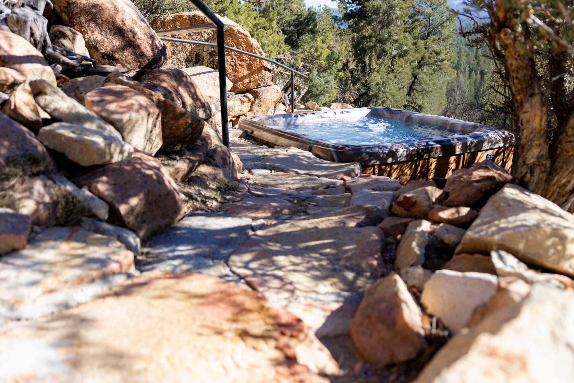 A hot tub surrounded by rocks and trees.