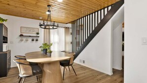 A dining area with a round table, chairs, a chandelier, and a staircase. - 2613-shiloh Woods Cabin (Big Bear Lake)