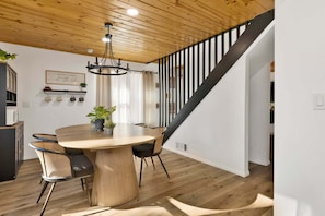 A dining area with a wooden table, chairs, and a chandelier. - 2613-shiloh Woods Cabin (Big Bear Lake)