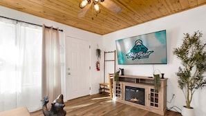 A living room with a fireplace, a television mounted on the wall, and a wooden ceiling. - 2613-shiloh Woods Cabin (Big Bear Lake)