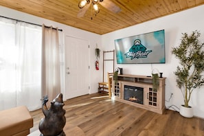 A living room with a fireplace, a mounted TV, and a wooden ceiling. - 2613-shiloh Woods Cabin (Big Bear Lake)