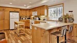 A kitchen with wooden cabinets, a refrigerator, a stove, a sink, and a window. - Brownie Resort #2618 (Big Bear Lake)