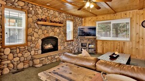 A stone fireplace, wooden ceiling, and a stone wall. - Brownie Resort #2618 (Big Bear Lake)