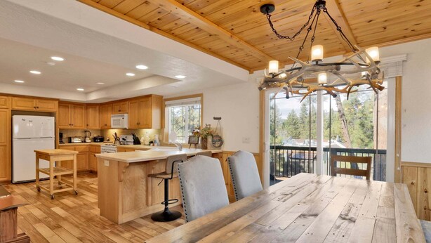 A spacious kitchen with wooden cabinets, a central island, and a dining area with a large wooden table and chairs. - Brownie Resort #2618 (Big Bear Lake)