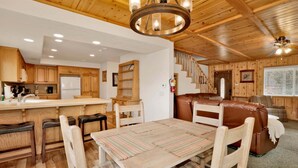 Un intérieur en bois comprenant une table à manger, des chaises, un canapé, un escalier et un coin cuisine.