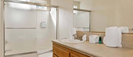 A bathroom with a shower, toilet, sink, and mirror.