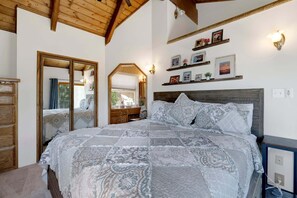 Ein Schlafzimmer mit einem großen Bett, einem Holzkopfende, einem Spiegel und Regalen an der Wand mit Bildern.